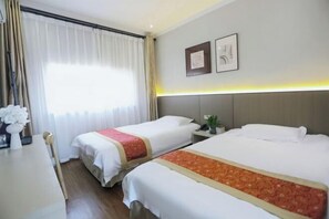 Quarto de hotel com duas camas, uma escrivaninha com cadeira, uma janela com cortinas e uma mesa de cabeceira com uma planta.
