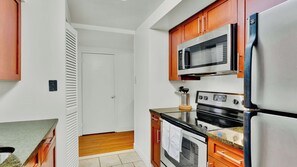 Eine Küche mit Holzausstattung, einer Mikrowelle, einem Kühlschrank und einem Backofen.