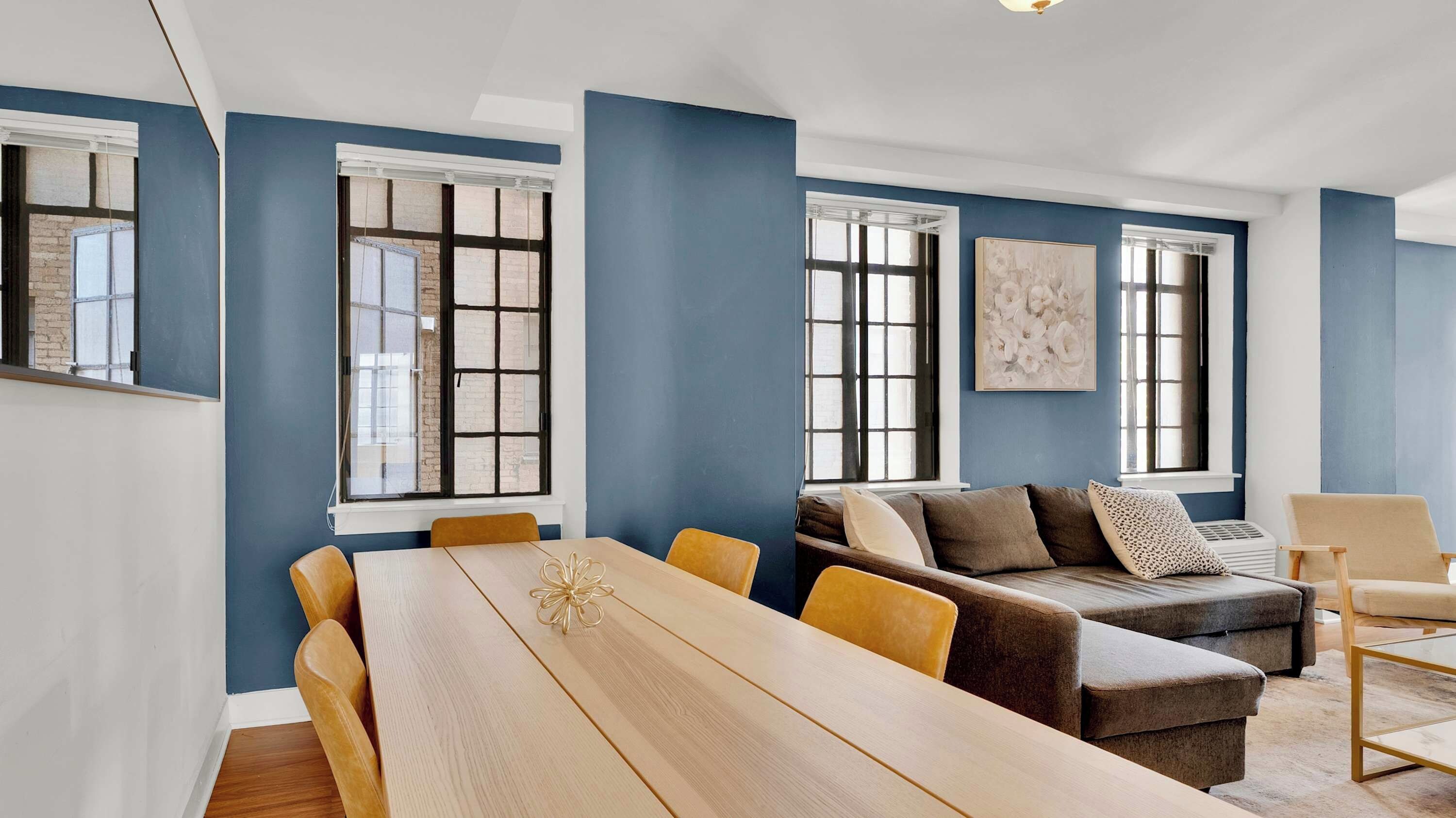A modern living room with a long wooden table, a sofa, and a chair.
