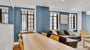 A modern living room with a long wooden table, a sofa, and a chair.