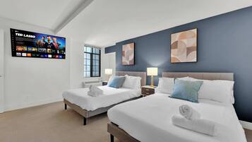 Une chambre d’hôtel avec deux lits, un téléviseur fixé au mur et des œuvres d’art abstraites accrochées aux murs.