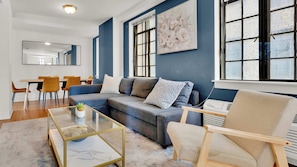 A living room with a sofa, armchairs, a coffee table, and a dining area with chairs. - Modern 2BD | Center City | 4 Beds | Near JFK Plaza (Philadelphia)