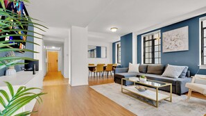 A modern living room with a sofa, coffee table, and a dining area with chairs.