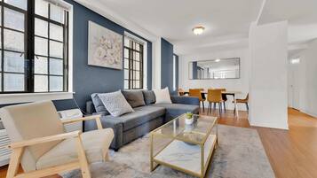 A modern living room with a sofa, armchair, coffee table, and dining area.