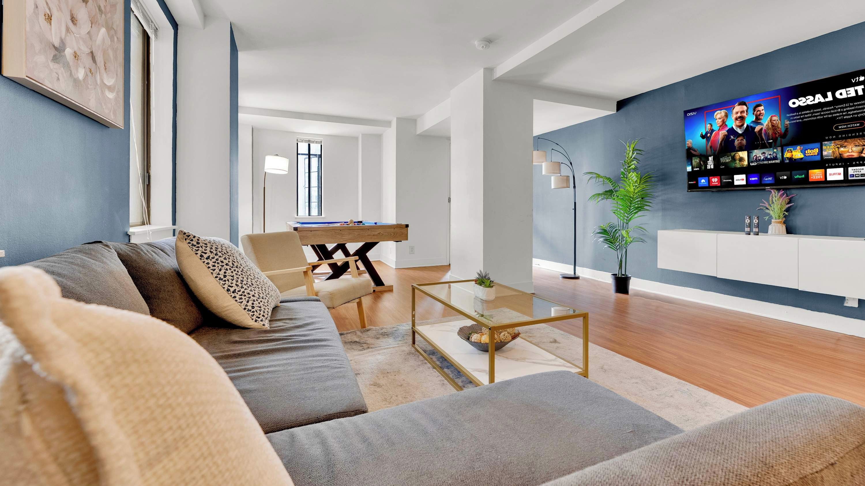 Un salon moderne avec un canapé, une table basse et un téléviseur à écran plat fixé au mur.