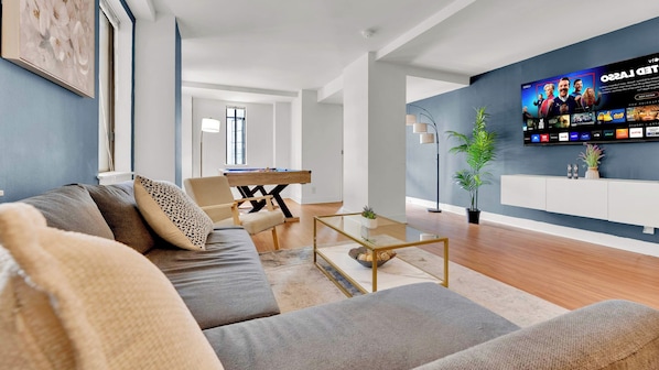 A modern living room with a sofa, coffee table, and a flat-screen TV mounted on the wall. - Modern 2BD | Center City | 4 Beds | Near JFK Plaza (Philadelphia)