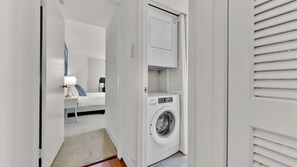 A laundry room with a washing machine and a drying rack.