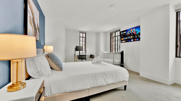 A modern bedroom with a bed, bedside table, lamp, and a TV mounted on the wall.