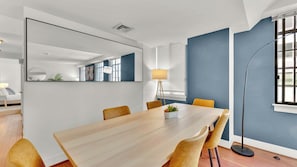 A modern dining area with a wooden table, yellow chairs, a large mirror, and a floor lamp.