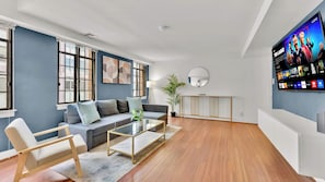 A modern living room with a sofa, coffee table, and a TV mounted on the wall.