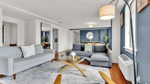 Ein modernes Wohnzimmer mit zwei Sofas, einem Couchtisch und einem Essbereich im Hintergrund.