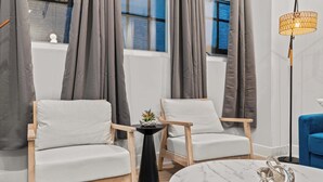 A modern living room with two white armchairs, a small black side table with a plant, a marble coffee table, and a floor lamp. - Modern 3-Bedroom Oasis in Center City (Philadelphia)