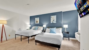 A hotel room with two beds, a flat-screen TV mounted on the wall, and a floor lamp. - Luxury 2BD | Center City | 4 Beds | Near LOVE Park (Philadelphia)