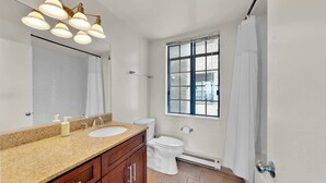 A bathroom with two sinks, a toilet, a window with a view, and a shower curtain.