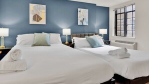 A hotel room with two beds, white linens, and artwork on the walls.