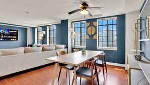 A modern living room with a sofa, dining table, chairs, and a ceiling fan.