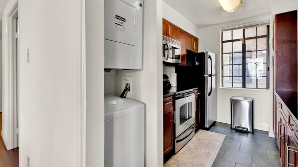 A modern kitchen with white appliances, wooden cabinets, and a large window.
