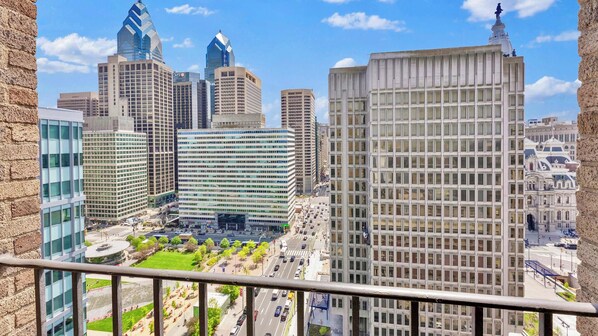 A cityscape with modern high-rise buildings, a central plaza, and a historic building with a statue.