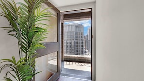 A balcony with a view of tall buildings, a potted plant, and a door leading to the interior. - Luxury 2BD | Center City | 6 Beds | By JFK plaza (Philadelphia)
