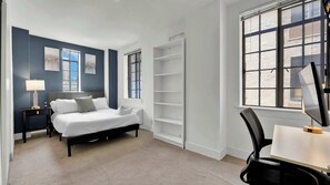 A modern hotel room with a bed, bedside tables, a desk, and a chair. - Luxury 2BD | Center City | 6 Beds | By JFK plaza (Philadelphia)