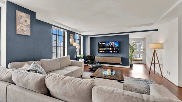 Una sala moderna con un sofá, una mesa de centro y un televisor montado en la pared.