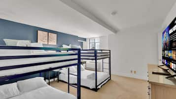 Une chambre avec des lits superposés, un téléviseur à écran plat et une fenêtre avec des stores.