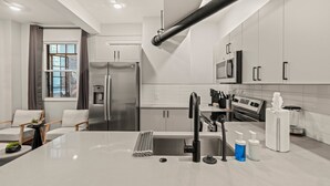 A modern kitchen with a central island, stainless steel appliances, and a large window with curtains.