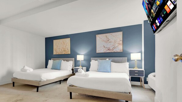 Ein Hotelzimmer mit zwei Betten, einem Flachbildfernseher und Kunstwerken an den Wänden.