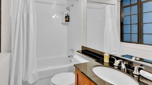 A bathroom with a bathtub, a toilet, a sink, and a mirror.