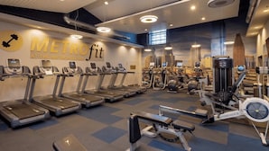 A gym with treadmills, weight machines, and a wall mural.