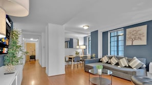 A modern living room with a grey sofa, a coffee table, and a dining area with a table and chairs.