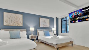 A hotel room with two beds, a TV mounted on the wall, and artwork on the walls.