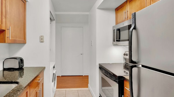 A kitchen with wooden cabinets, a microwave, a toaster, and a dishwasher. - Stylish 2BD | Center City | 5 Beds | By JFK Plaza (Philadelphia)
