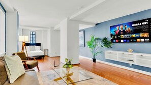 Ein modernes Wohnzimmer mit Flachbildfernseher, einer Couch, einem Couchtisch und einem Blumentopf.