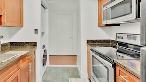 Eine kleine Küche mit Mikrowelle, Backofen und Arbeitsplatten aus Granit.
