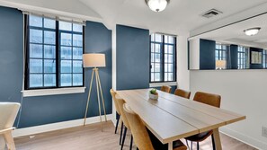 A modern meeting room with a long table, chairs, a lamp, and large windows.