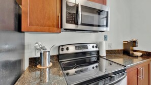 Cozinha equipada com micro-ondas, fogão e cafeteira.