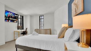A hotel room with a bed, a desk, a television, and a window.