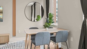 A dining area with a round mirror, a wooden table, four grey chairs, a potted plant, and a window with curtains. - Luxury Studio | 1 Bed | Northern Liberties (Philadelphia)