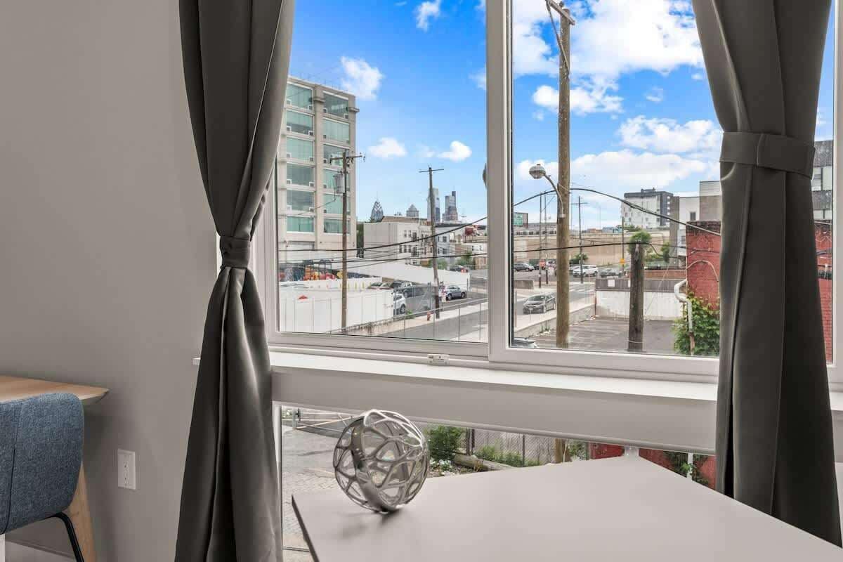 A room with a large window, a table, a chair, and a decorative sphere.