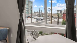 A room with a large window, a table, a chair, and a decorative sphere. - Luxury Studio | 1 Bed | Northern Liberties (Philadelphia)