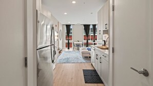 Eine moderne Küche mit weißen Schränken, einem Edelstahl-Kühlschrank und einem Essbereich mit Tisch und Stühlen.