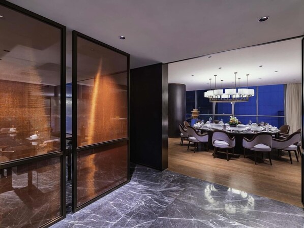 A modern dining area with a marble floor, a large table set for six, and a chandelier. - Novotel Xian Xixian (Xianyang)