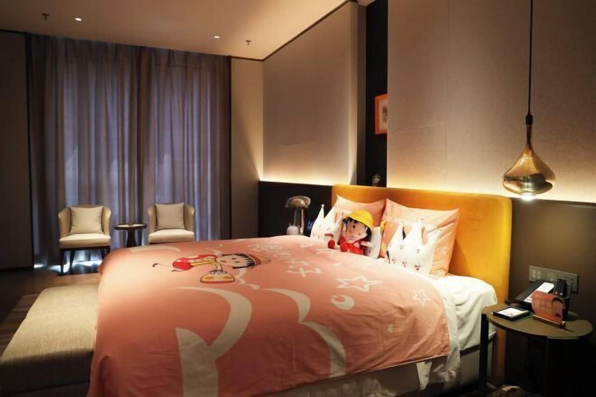 Ein Hotelzimmer mit einem großen Bett, zwei Stühlen, einem Nachttisch und einer Lampe.