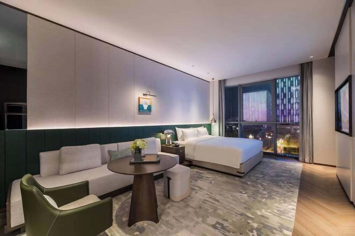 Ein modernes Hotelzimmer mit Bett, Sofa, kleinem Tisch und Nachttisch.