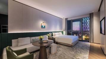 A modern hotel room with a bed, sofa, and a small table.
