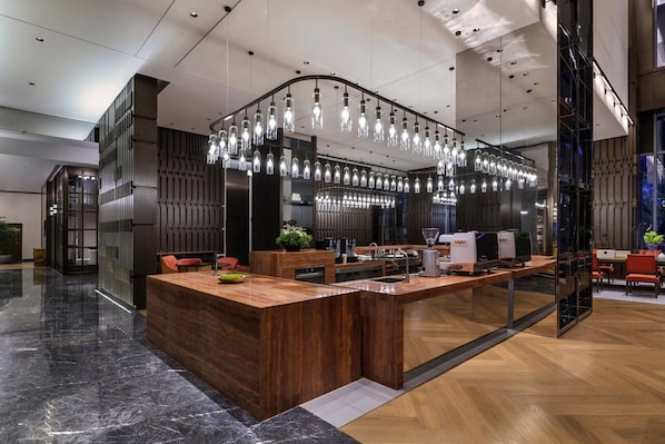 A modern kitchen with a central island, pendant lighting, and a view of the city at night.