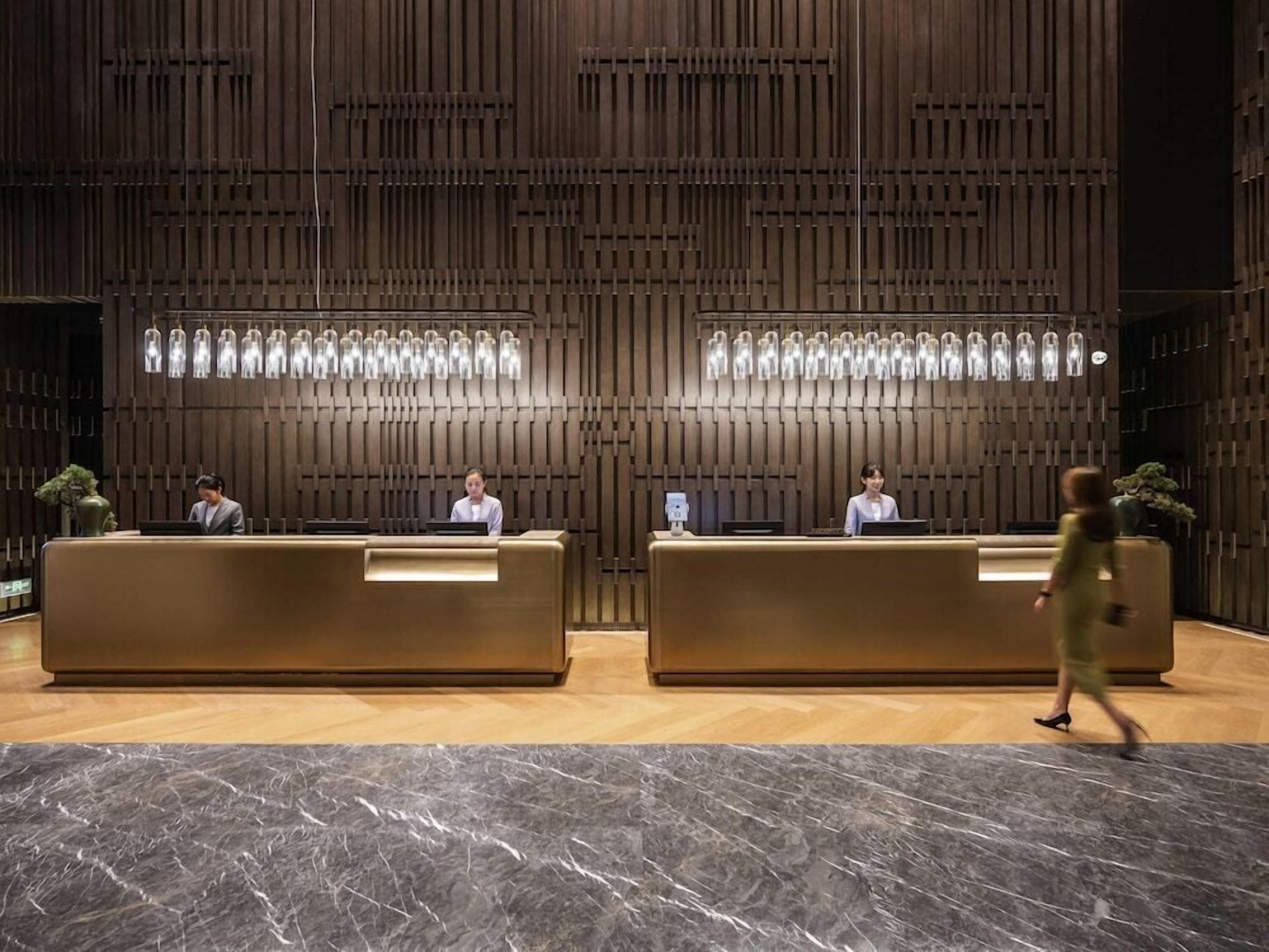Un área de recepción con dos mostradores, piso de mármol y pared con diseño.
