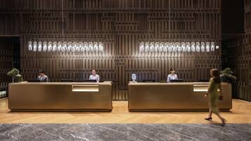 Un área de recepción con dos mostradores, piso de mármol y pared con diseño.