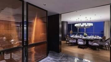 A modern dining area with a marble floor, a round table set for six, and a chandelier.
